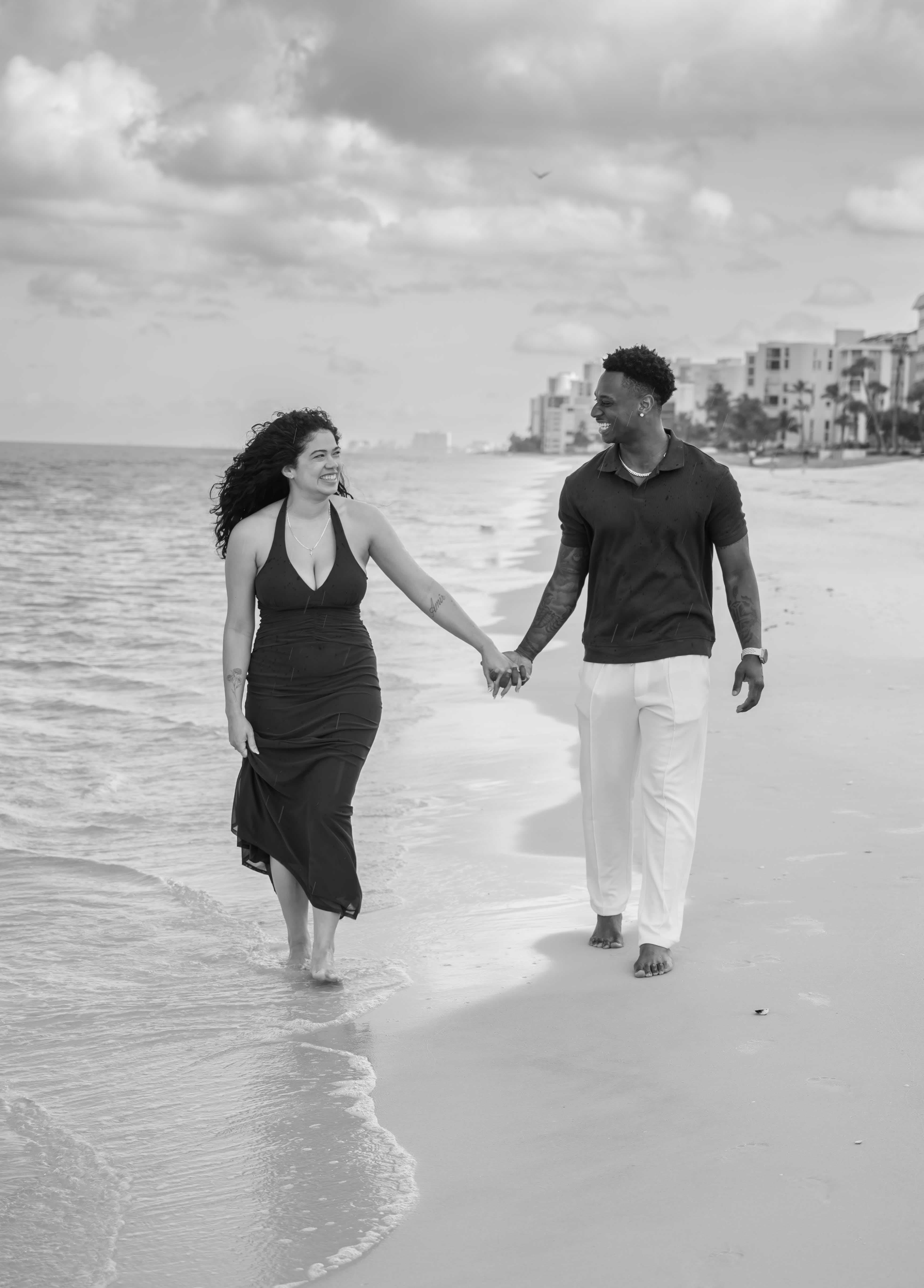 Couple walking hand in hand on the beach, black and white