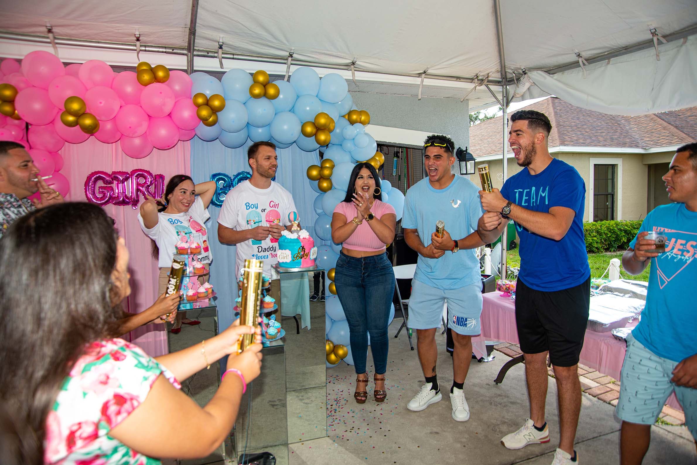 Family celebrating with confetti poppers at a gender reveal party