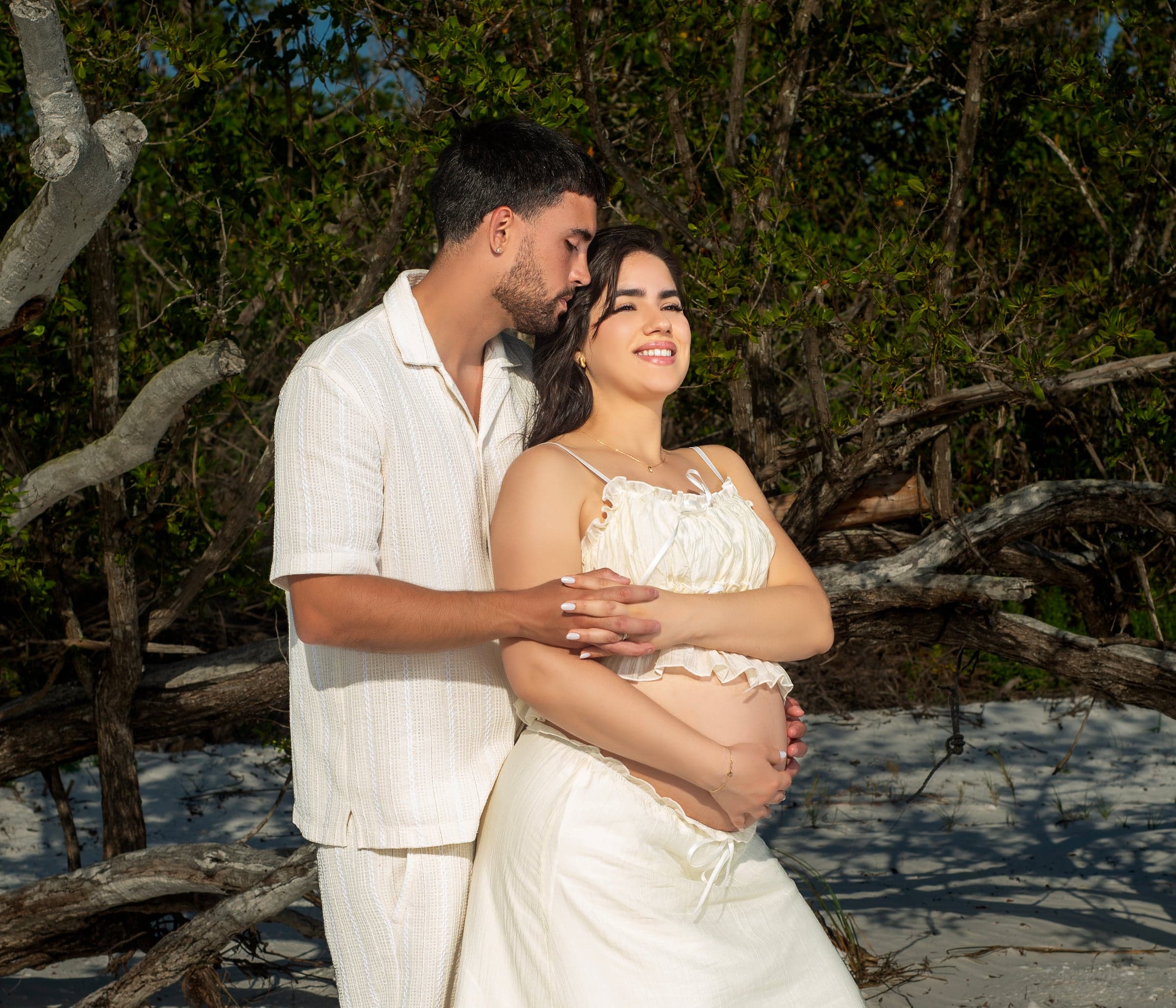 Maternity couple portrait among driftwood trees, SWFL beach