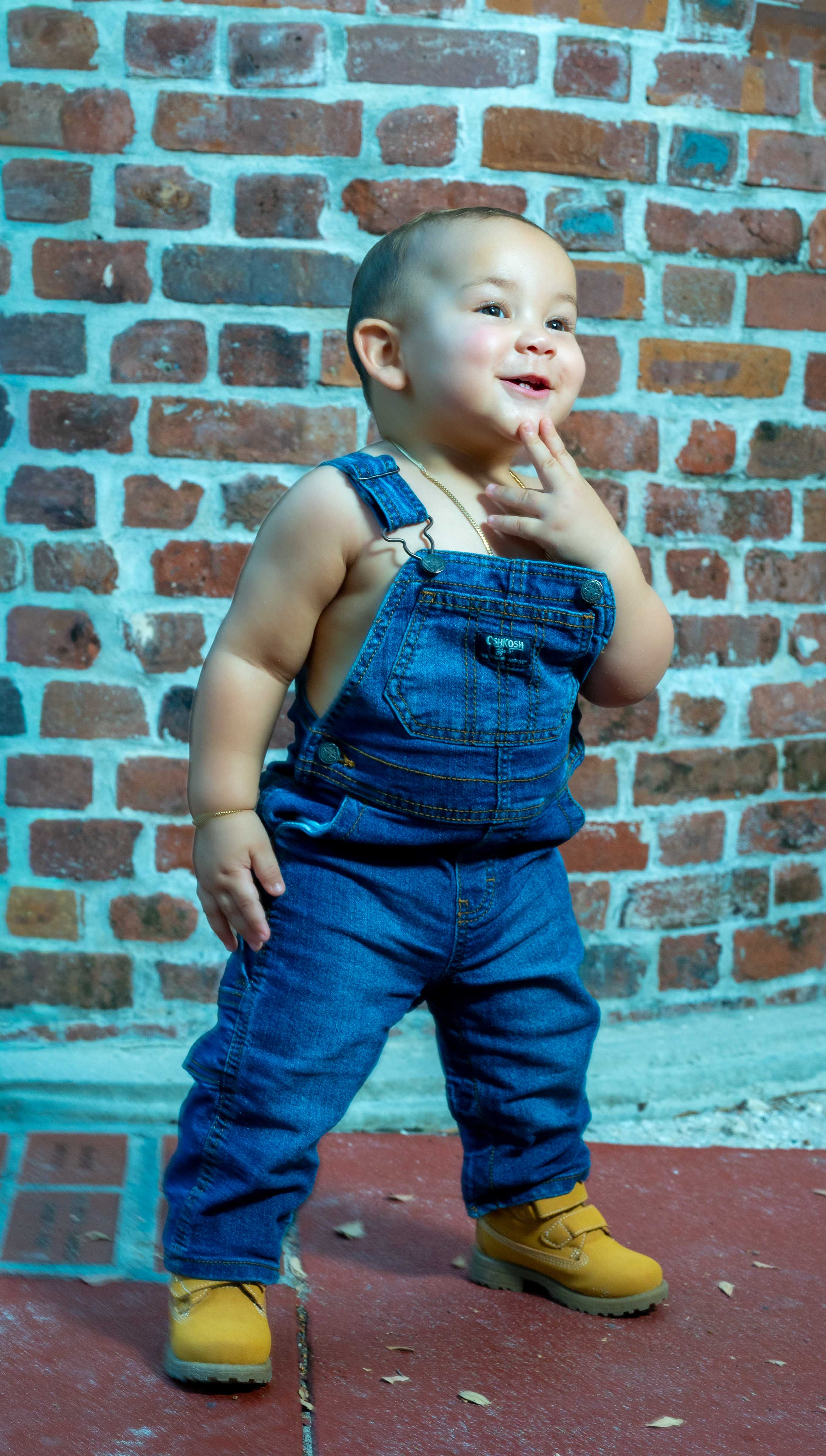 Baby portrait smiling against a brick wall
