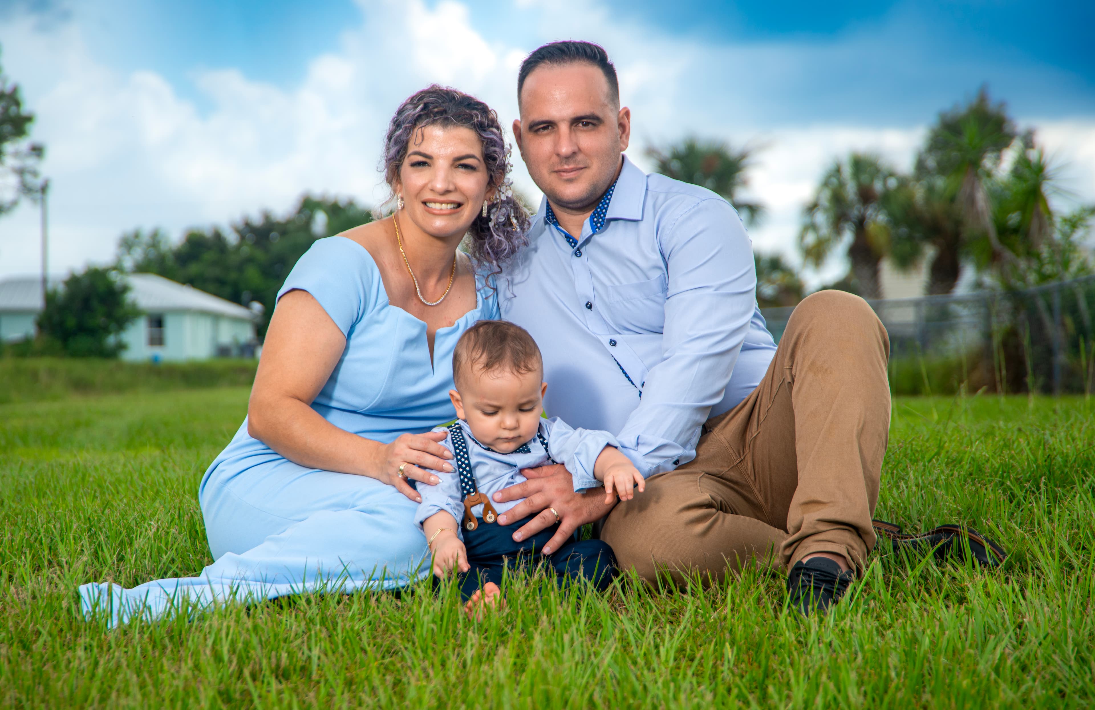 Family of three portrait sitting in the grass